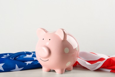 Photo of Piggy bank and American flag on white wooden table