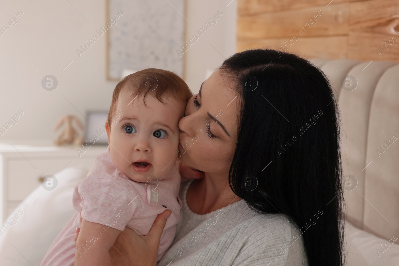 Photo of Happy woman with her little baby on bed at home