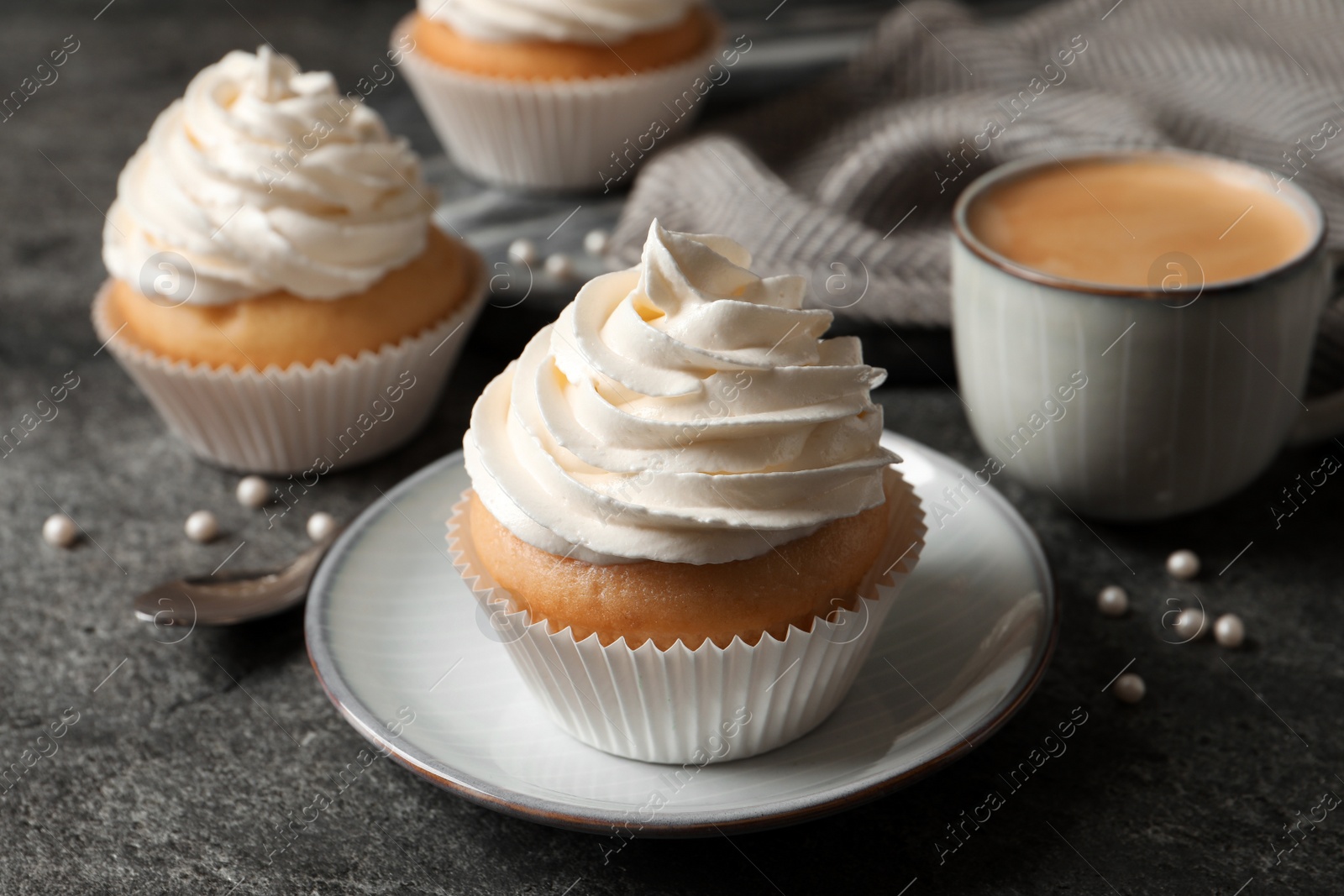 Photo of Delicious cupcakes with cream and cup of coffee on grey table, closeup