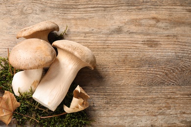Fresh wild mushrooms on wooden background, top view. Space for text