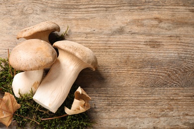 Photo of Fresh wild mushrooms on wooden background, top view. Space for text