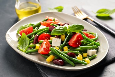 Photo of Tasty salad with green beans served on black table, closeup