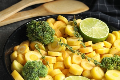 Photo of Raw yellow carrot with lime and broccoli in frying pan, closeup