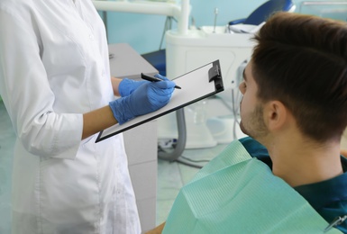 Photo of Professional dentist and patient in modern clinic