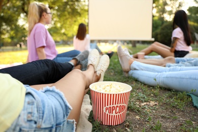 Young people with popcorn watching movie in open air cinema, closeup