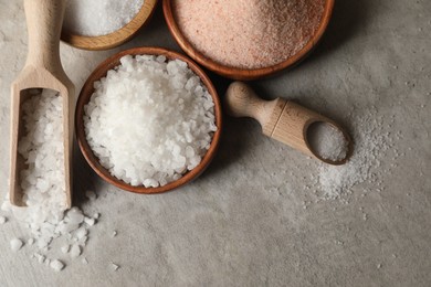 Photo of Different natural salt on grey textured table, flat lay. Space for text