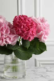 Vase with beautiful hortensia flowers on white marble table