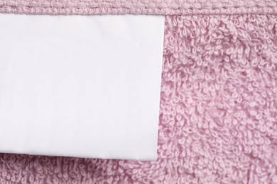 Photo of Clothing label on pink fluffy towel, top view. Space for text