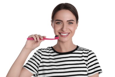 Young woman holding brush with charcoal toothpaste on white background