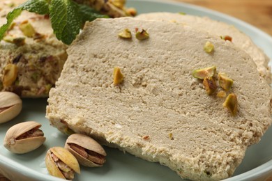 Photo of Tasty halva with pistachios and mint on table, closeup