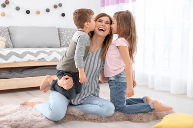 Photo of Cute little children kissing their nanny at home