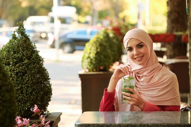 Photo of Muslim woman with cocktail in outdoor cafe