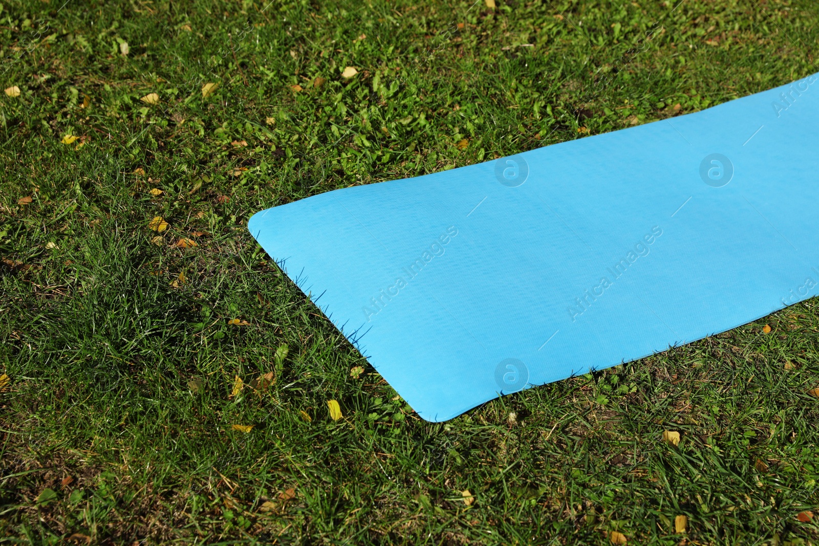 Photo of Bright karemat or fitness mat on fresh green grass outdoors, space for text