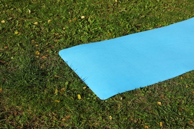 Photo of Bright karemat or fitness mat on fresh green grass outdoors, space for text