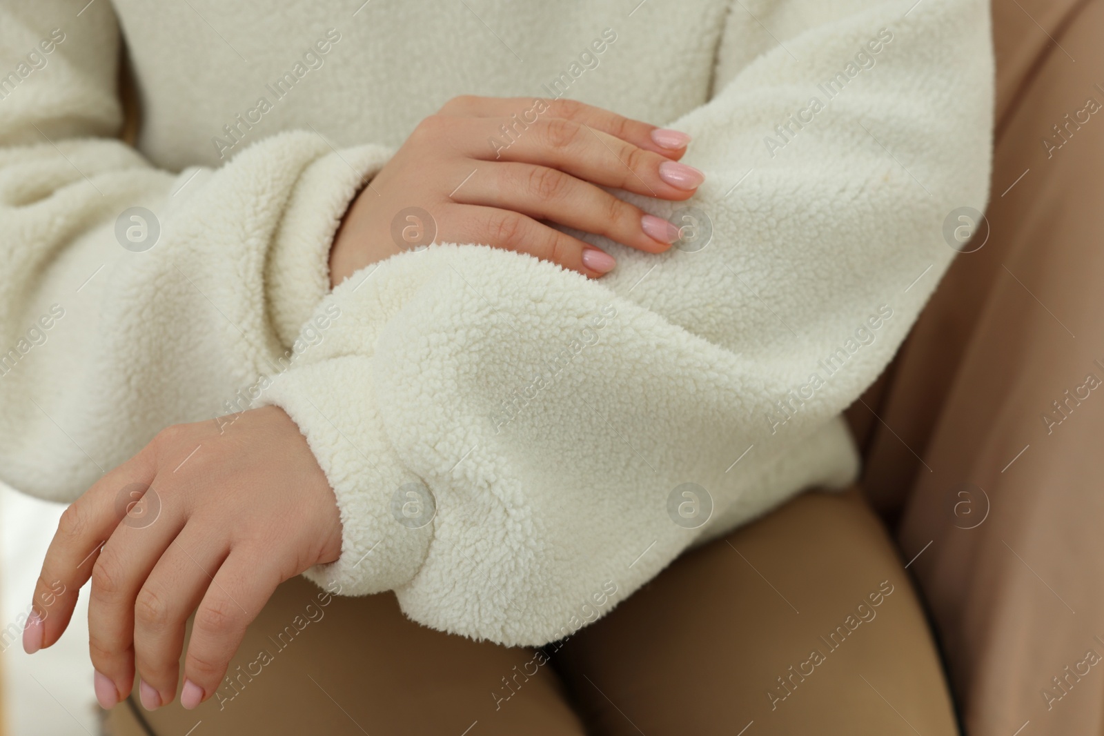 Photo of Woman touching sweater made of soft white fabric, closeup