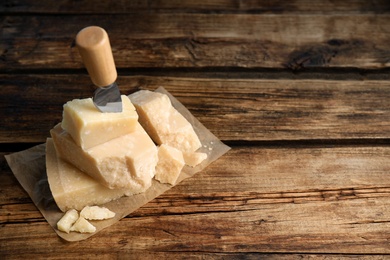 Photo of Delicious parmesan cheese and knife on wooden table. Space for text