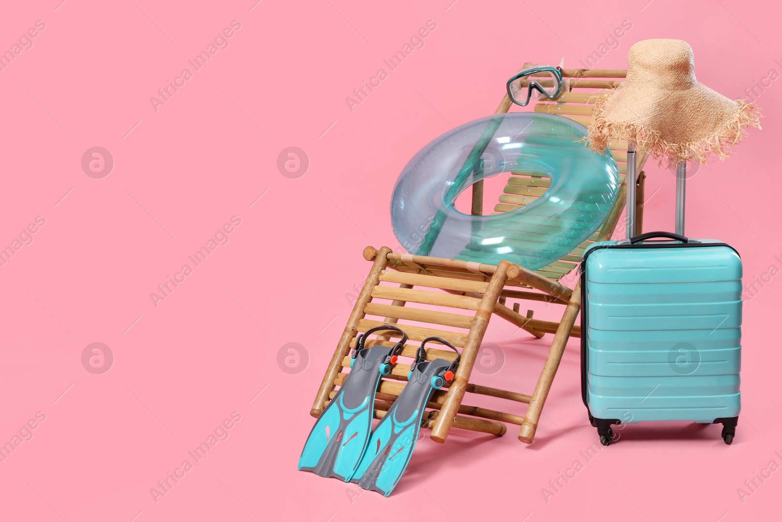 Photo of Deck chair, suitcase and beach accessories on pink background, space for text