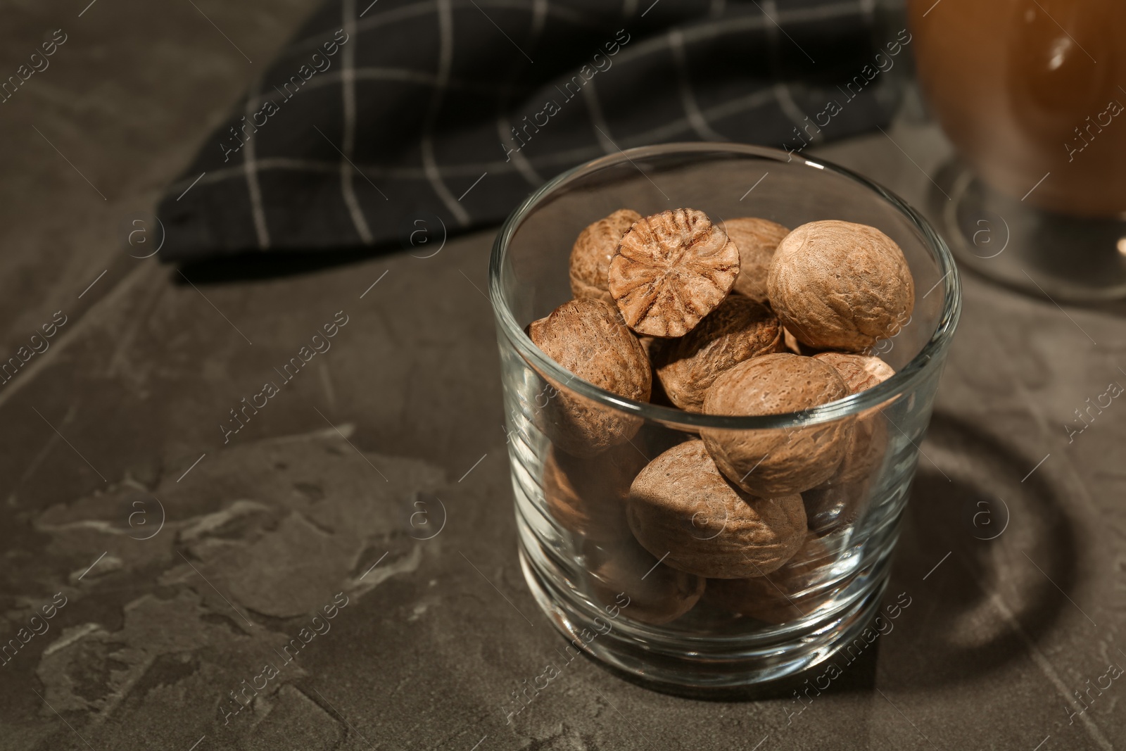 Photo of Nutmegs in glass on black table. Space for text