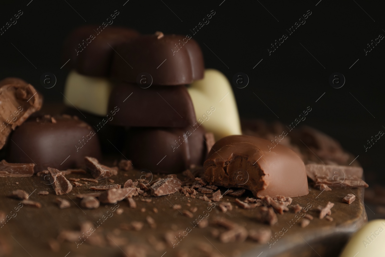 Photo of Beautiful heart shaped chocolate candies on wooden board, closeup