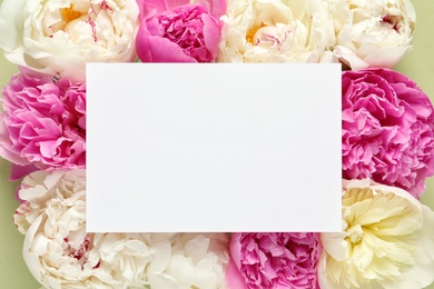 Photo of Fresh peonies and empty card on color background, flat lay with space for text