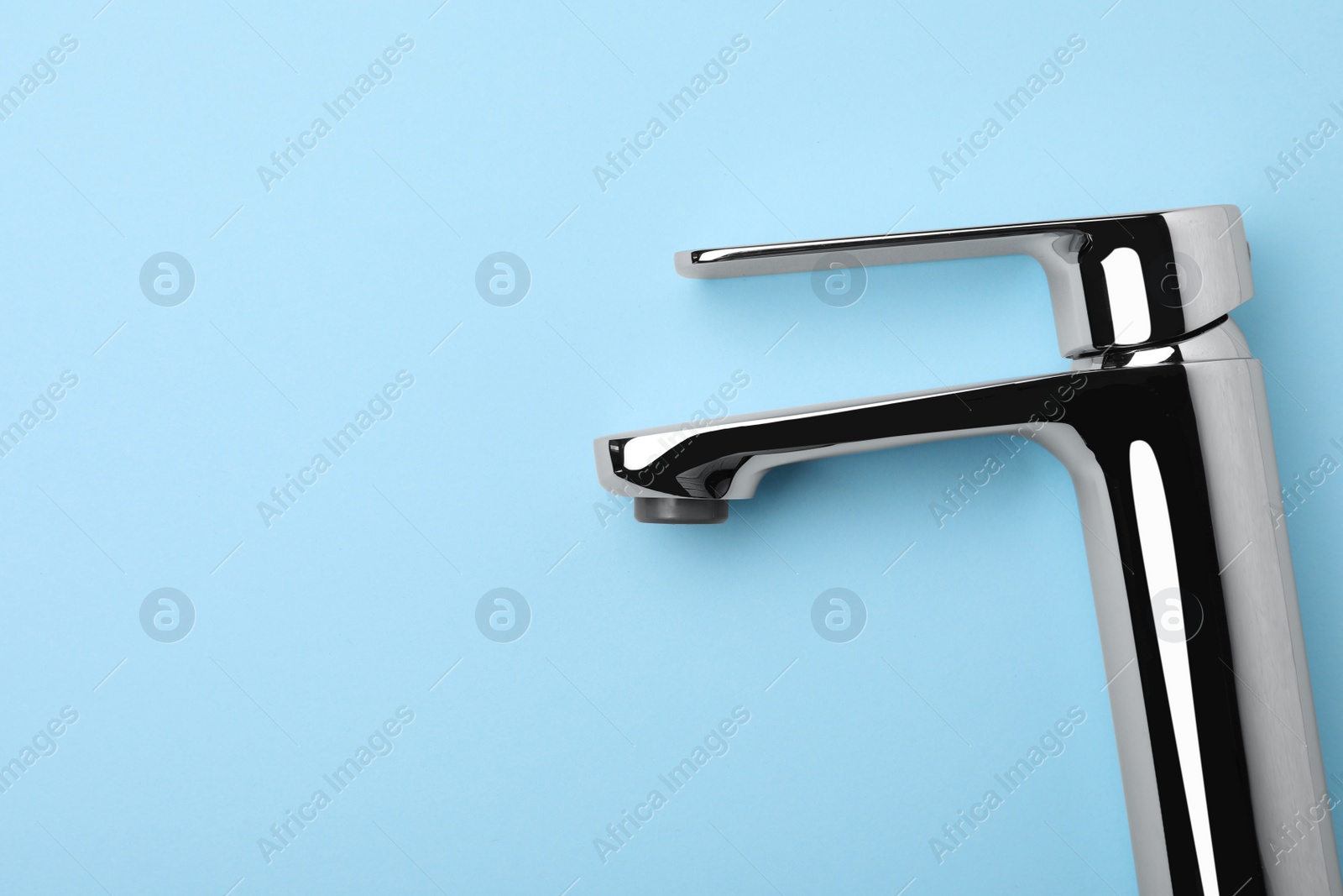 Photo of Single handle water tap on light blue background, top view. Space for text