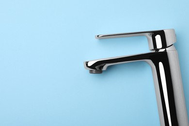 Single handle water tap on light blue background, top view. Space for text