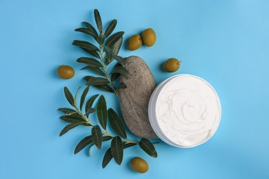 Flat lay composition with jar of cream and olives on light blue background