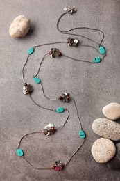Stylish necklace with gemstones and stones on grey background, flat lay