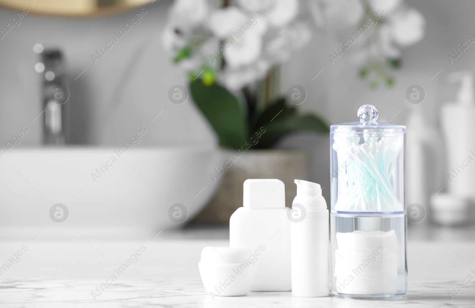 Photo of Cotton pads and swabs near cosmetic products on white countertop in bathroom. Space for text
