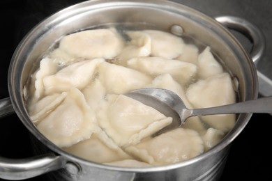Photo of Cooking dumplings (varenyky) with tasty filling in pot indoors, closeup