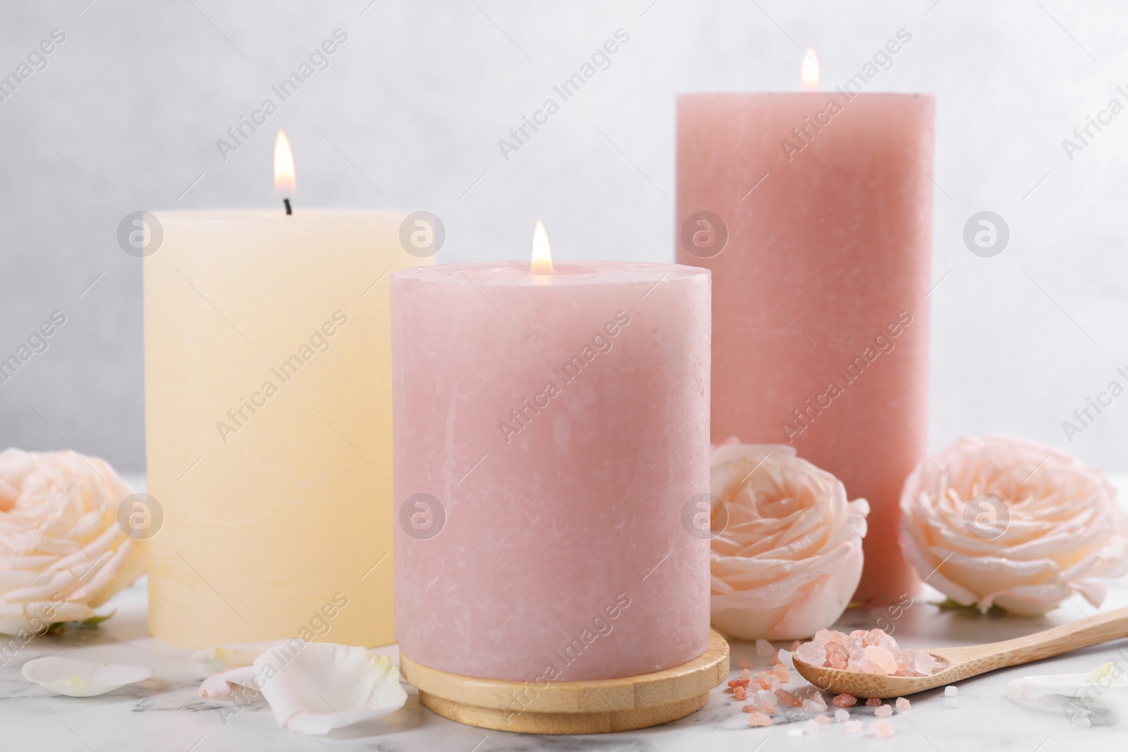 Photo of Spa composition with burning candles, flowers and sea salt on white marble table