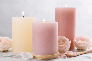 Photo of Spa composition with burning candles, flowers and sea salt on white marble table