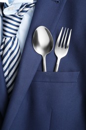 Photo of Cutlery in breast pocket of men`s jacket as background, closeup. Business lunch concept