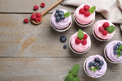 Photo of Sweet cupcakes with fresh berries on wooden table, flat lay. Space for text