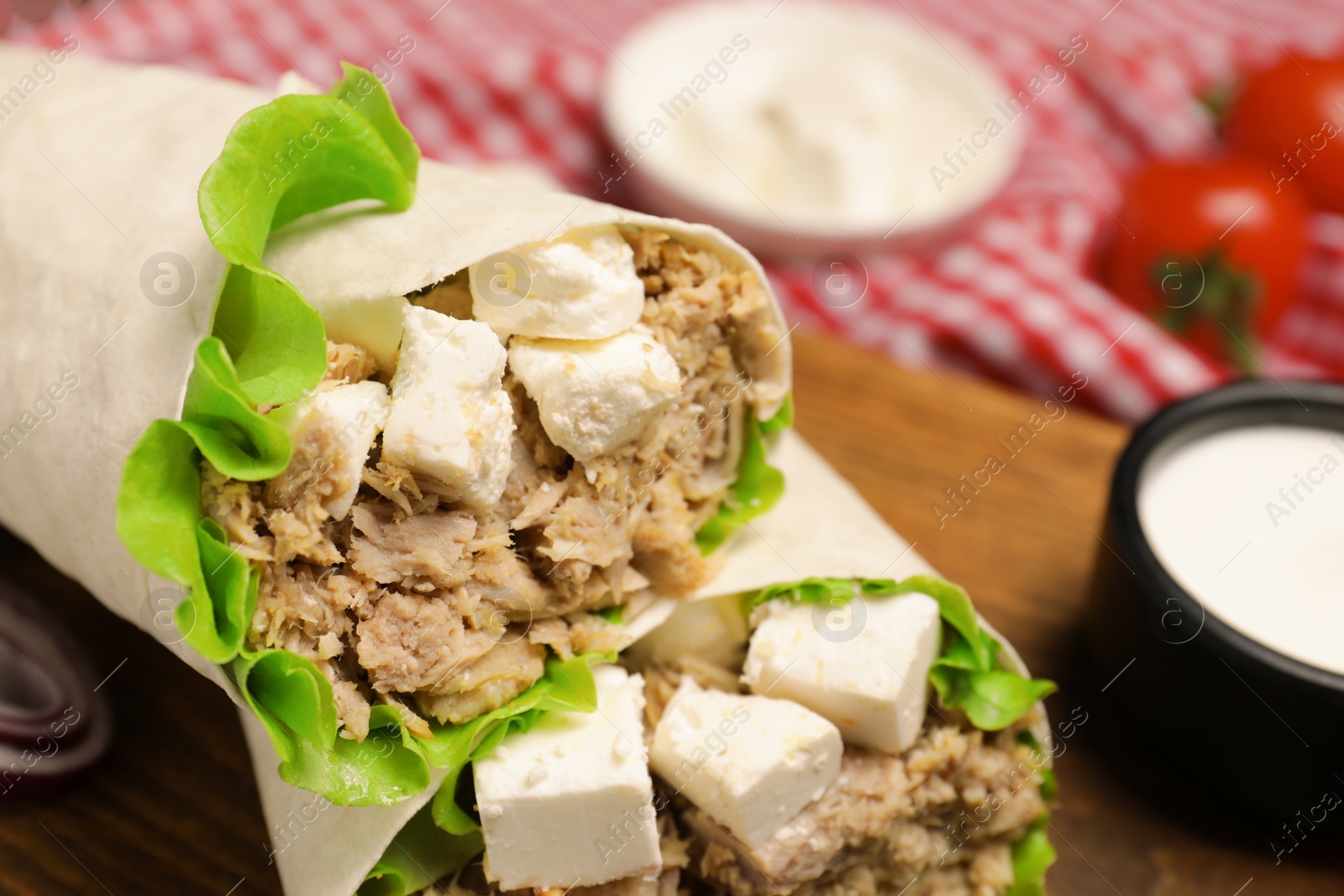 Photo of Delicious tortilla wraps with tuna on wooden board, closeup