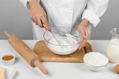 Photo of Woman whipping egg whites at wooden table, closeup. Baking pie