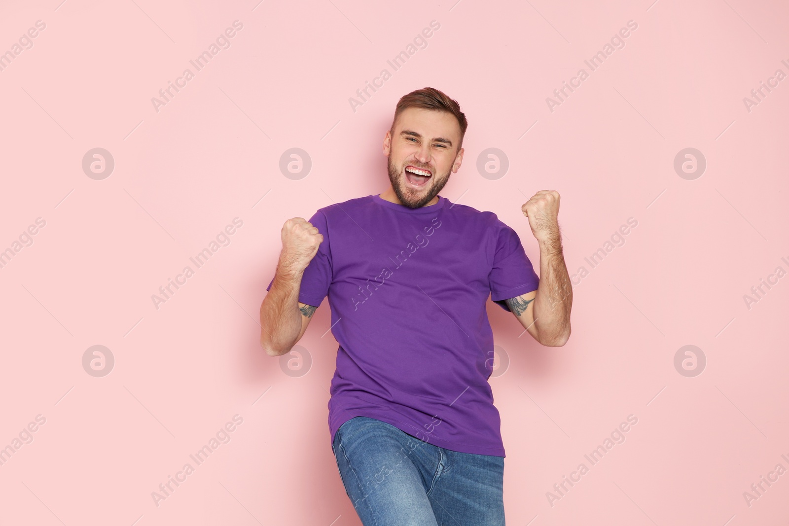 Photo of Young man celebrating victory on color background