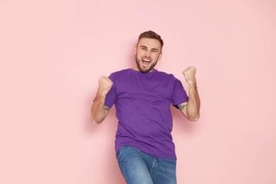 Photo of Young man celebrating victory on color background