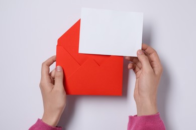 Photo of Woman with blank card and letter envelope at white table, top view. Space for text