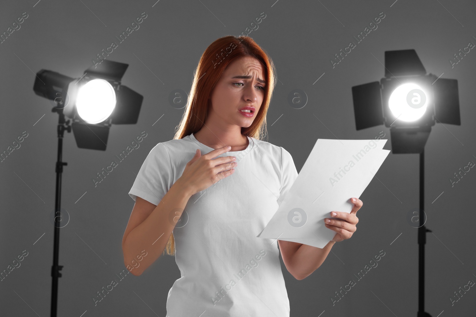 Photo of Casting call. Emotional woman with script performing on grey background in studio