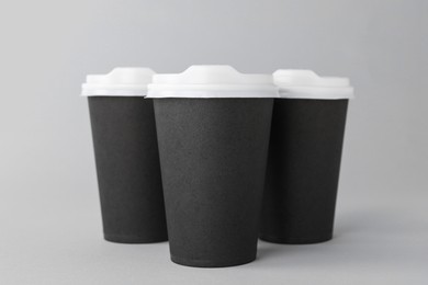 Photo of Paper cups with white lids on light grey background. Coffee to go