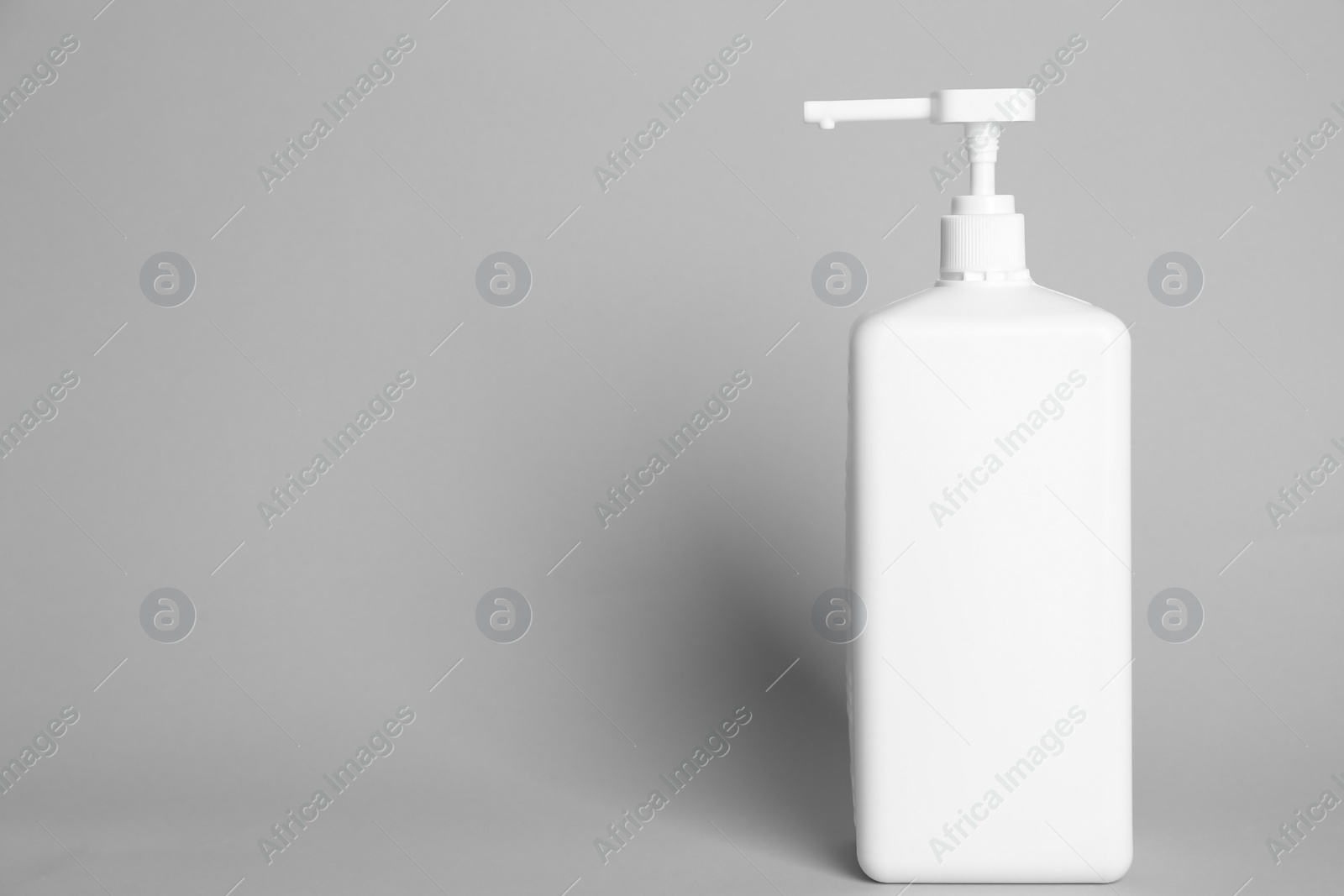 Photo of Dispenser bottle with antiseptic gel on light grey background. Space for text