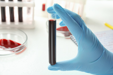 Image of Scientist holding test tube with blood sample, closeup. Laboratory analysis