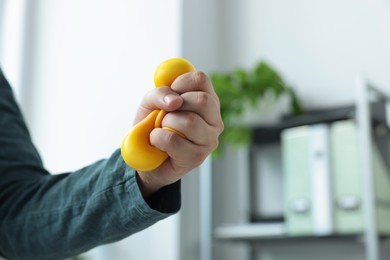 Photo of Man squeezing antistress ball in office, closeup
