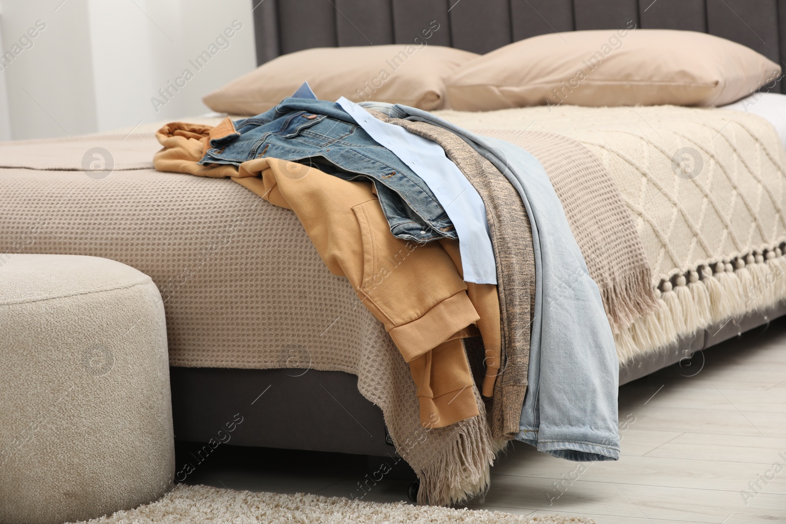 Photo of Pile of different clothes on bed at home