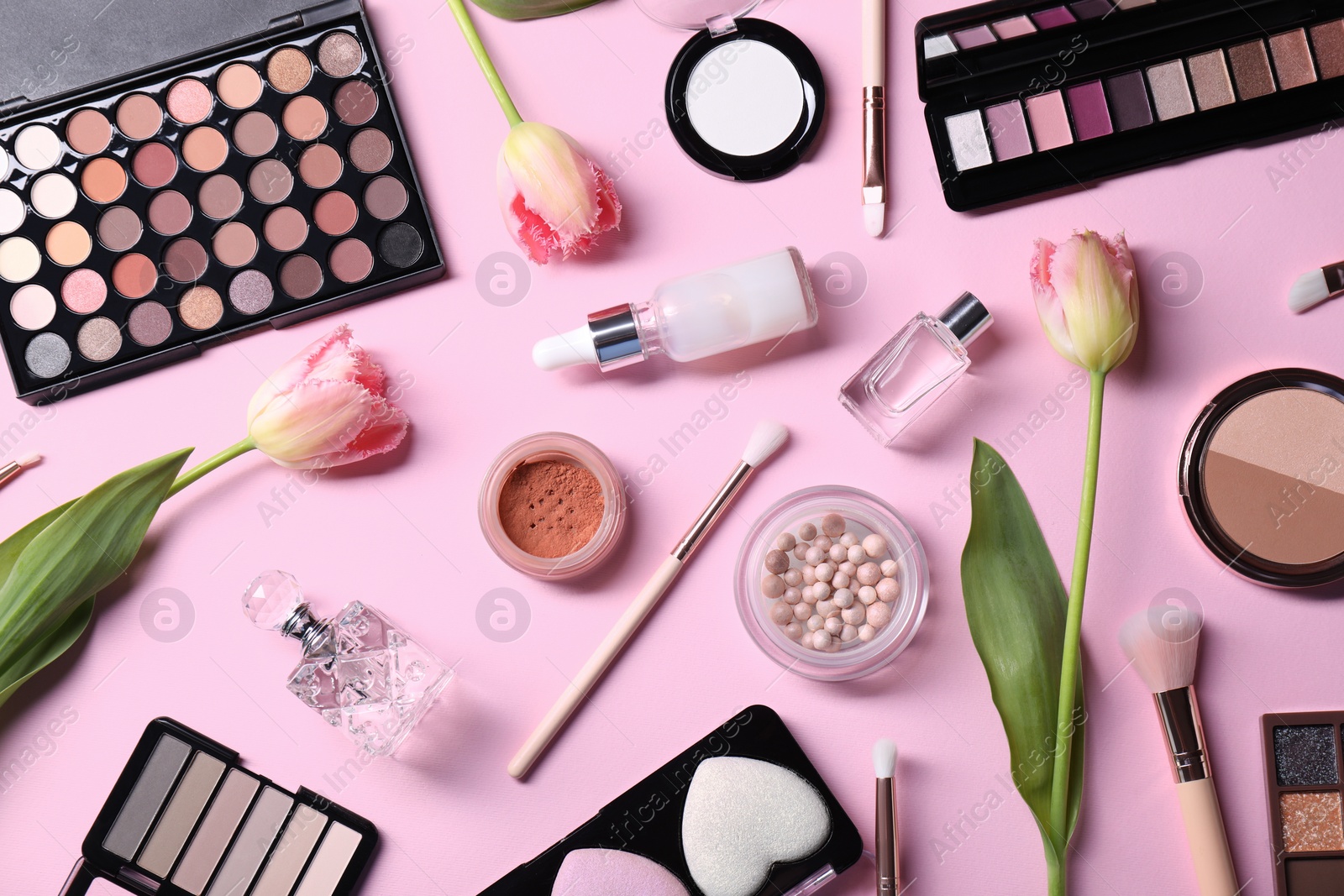 Photo of Flat lay composition with different makeup products and beautiful spring flowers on pink background