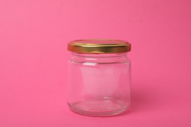 Photo of Closed empty glass jar on pink background