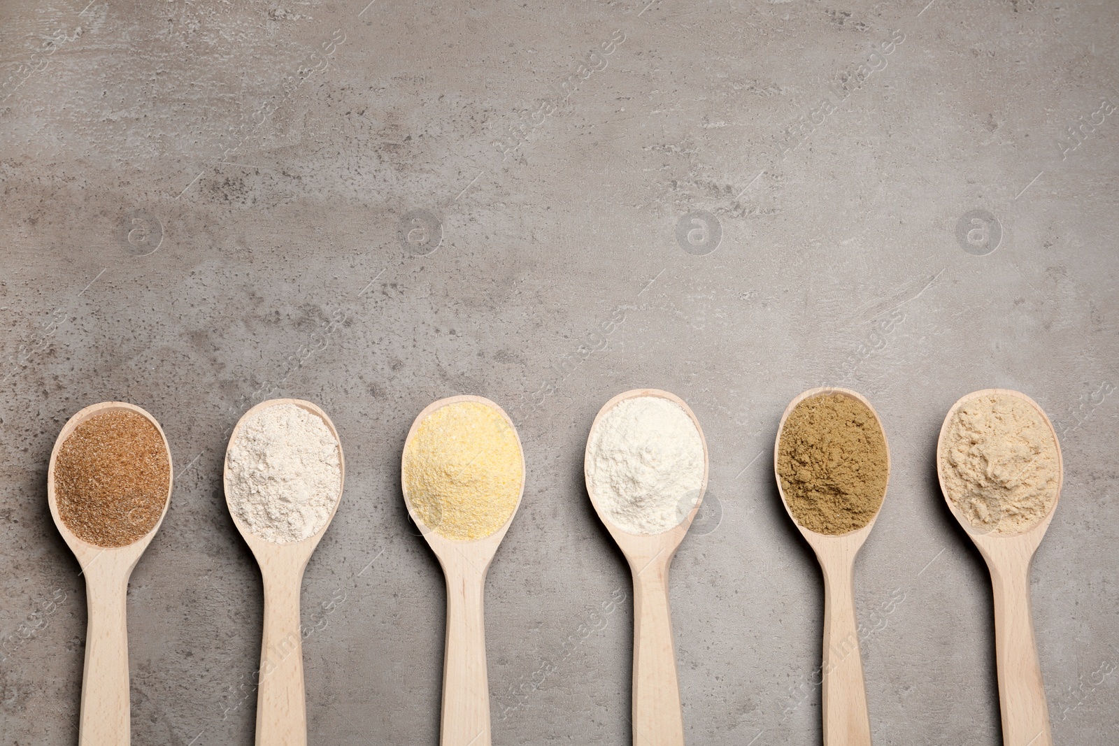 Photo of Spoons with different types of flour on table, top view. Space for text
