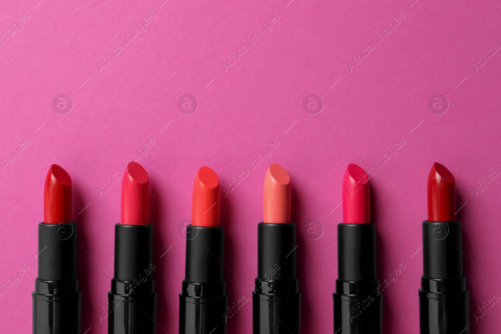 Photo of Beautiful lipsticks on pink background, flat lay. Space for text