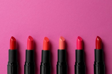 Photo of Beautiful lipsticks on pink background, flat lay. Space for text